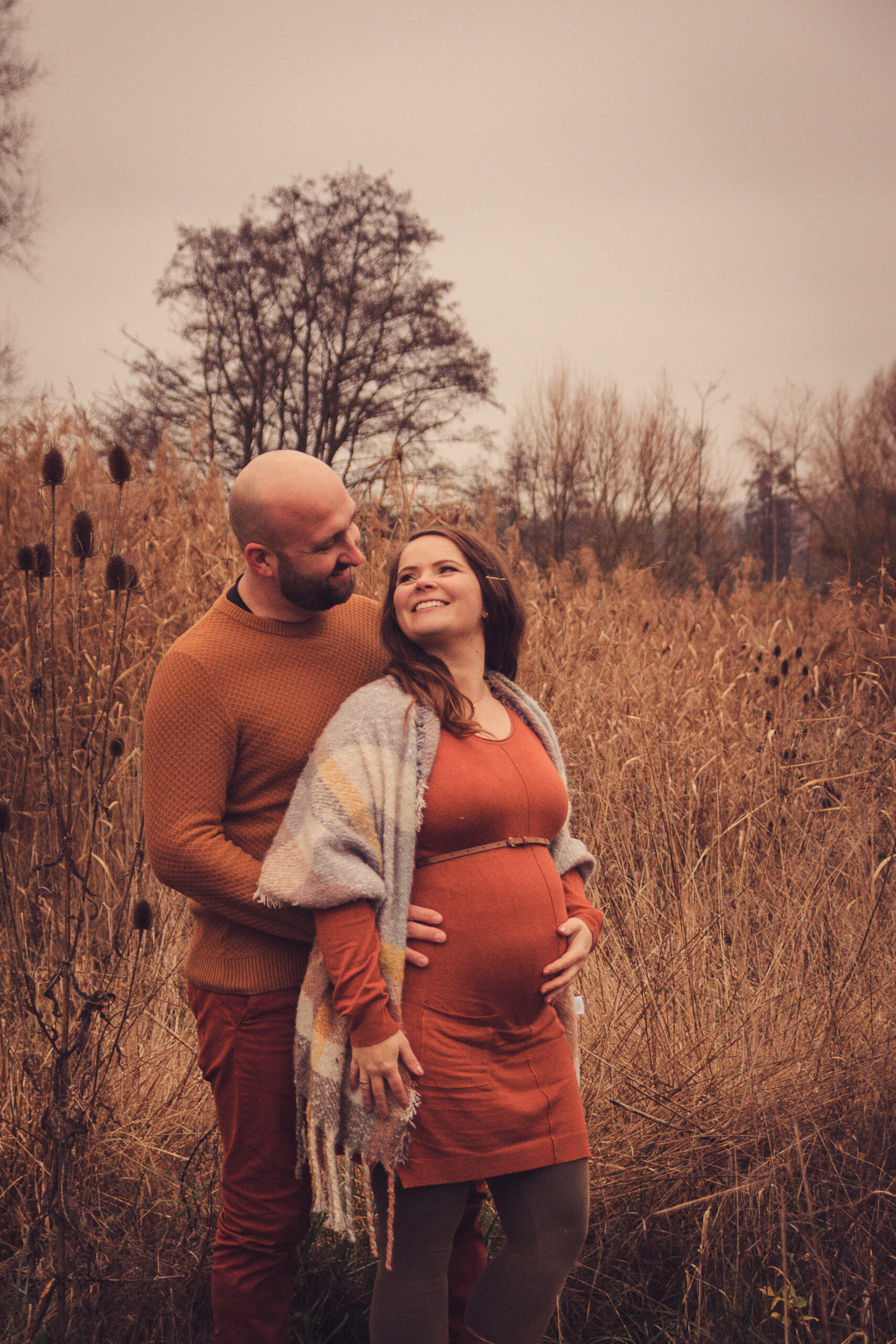 Schwangere Frau mit Babybauch im Arm des Partners babybauch shooting in der nähe schwangerschaftsfotos babybauch shooting