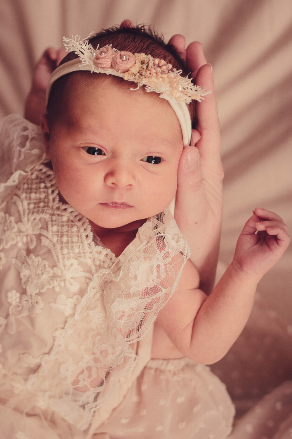 Neugeborenes im weißen Kleid auf den Händen gehalten newborn fotoshooting newborn shooting new born fotoshooting